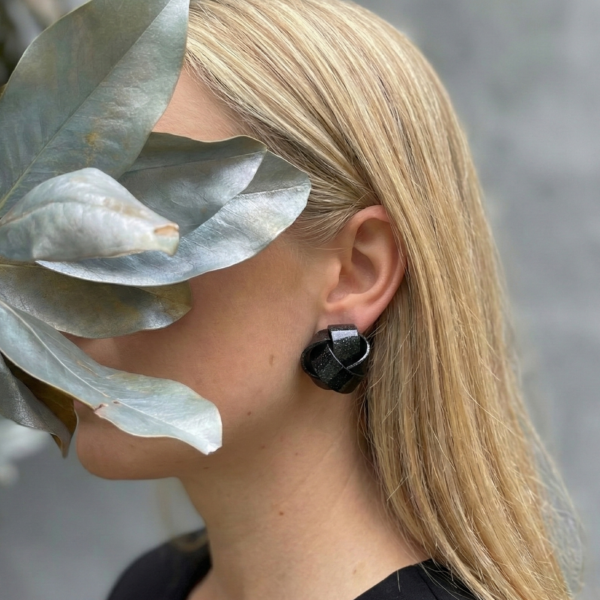 Modelo con pendientes MINI KOMBU negros inspirados en las algas kombu retorcidas.